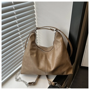 Détail du sac cabas en cuir PU marron avec coutures asymétriques et bandoulière en chaîne