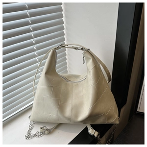 Détail d'un sac cabas crème minimaliste avec coutures géométriques et chaîne argentée