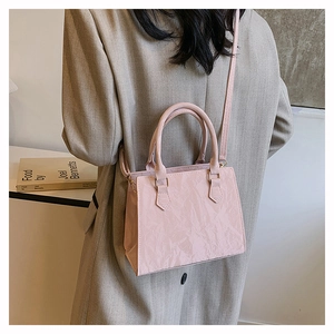 Detailed view of pink pleated PU leather tote bag worn with a casual khaki blazer