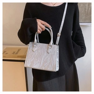 Chic light gray wrinkled tote bag with gold hardware shown on a model's arm for daily commute