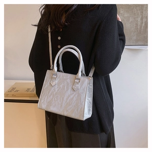 Detail of silver pleated texture on a large minimalist tote bag worn by a model