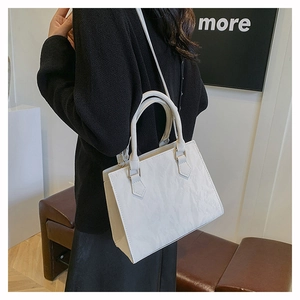 Detailed view of white tote bag with crinkled leather texture and gold hardware