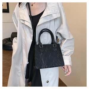 Detail view of the black textured tote bag with unique pleated finish and gold hardware