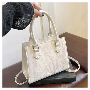 Detail of white pleated tote bag with golden hardware and matching shoulder strap