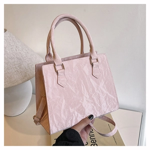 Detail of light pink tote bag featuring unique crinkled texture and cylindrical handles