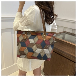 Detail of a large geometric patchwork tote bag with textured leather and gold rivets