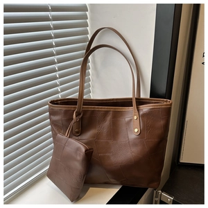 Detail of dark brown leather tote bag with patchwork texture and hanging small pouch
