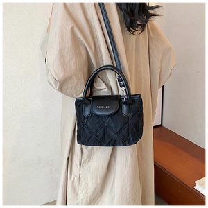 Detail of black quilted shoulder bag featuring premium stitching and long leather strap