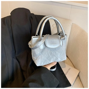 Detail of silver quilted bucket bag with metallic texture on a black suit backdrop