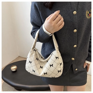 Detail of cream corduroy hobo bag featuring black diamond patterns and bow accents