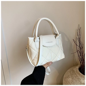 Detail of cream quilted bucket bag with polished finish and embossed fashion lettering