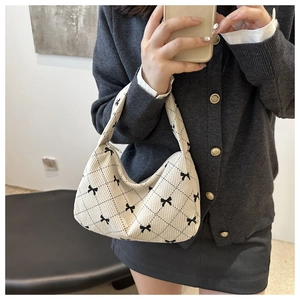 Detail of beige tote bag with black diamond pattern and bow decoration texture