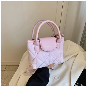 Pink quilted bucket bag with cylindrical handles and white text detail shown in hand