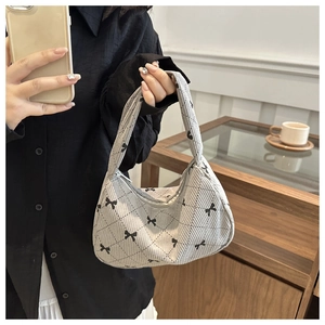 Detail of grey corduroy crescent bag with bow patterns and diamond quilting texture