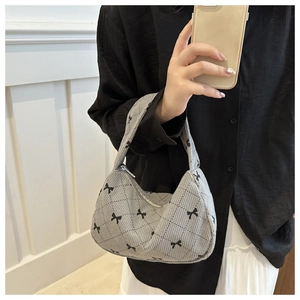 Close-up of grey corduroy pillow bag with black bow patterns and quilted stitching