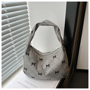 Detail of light gray corduroy hobo bag with quilted diamond pattern and bow print