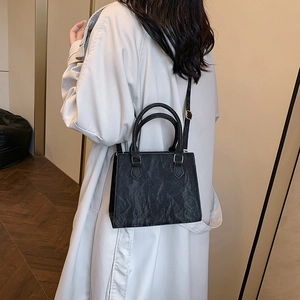 Minimalist black tote bag with ruched texture shown on shoulder for a stylish look