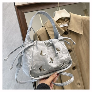 Close-up of light gray pleated bucket bag featuring silver butterfly metal charms