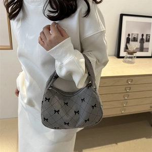 Gray corduroy hobo bag with quilted diamond pattern and cute black bows in daily life