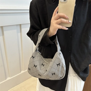 Sac sous le bras en velours côtelé gris avec nœuds et motif matelassé tenu par modèle