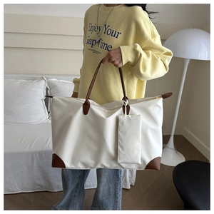 Detail of white nylon tote bag featuring brown leather handles and side zip pouch accessory