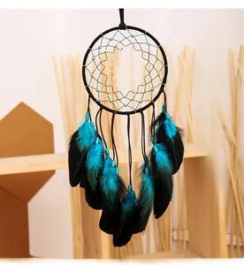 Vue détaillée d'un attrape-rêves artisanal avec plumes bleues sur un mur blanc