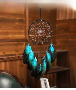 Détail d'attrape-rêves artisanal avec plumes noires aux pointes bleues sur mur en bois