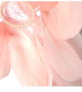 Detail eines rosa Traumfängers mit weichen Federn und Perlen für Fensterdekoration