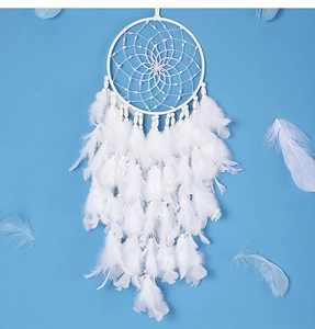Detail van witte handgemaakte dromenvanger met veren en roze kralen op blauwe achtergrond