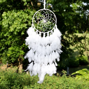 Handgemaakte witte dromenvanger met veren hangend in een natuurlijke groene tuin
