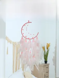 Detail of pink moon-shaped dream catcher with woven beads and soft fluffy feathers