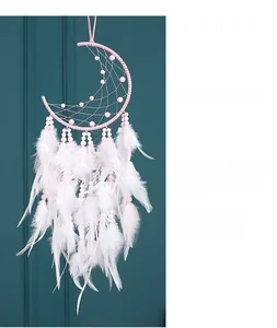 Pink moon dreamcatcher with white feathers and delicate beads hanging on a wall