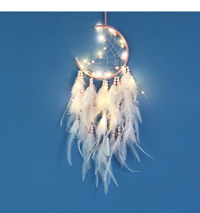 Detail of pink moon-shaped dream catcher with soft white feathers and warm glowing LED lights