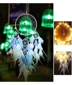 Detailed view of handmade dreamcatcher with glowing LED lights and soft blue feathers