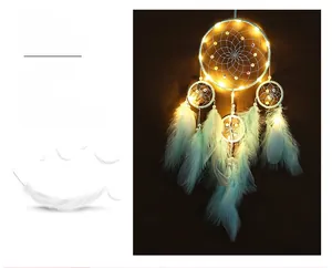 Macro detail of LED dreamcatcher showing blue feathers and warm glowing string lights