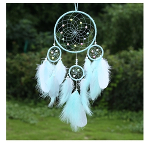 Close-up of mint green dream catcher with colorful beads and soft hanging feathers