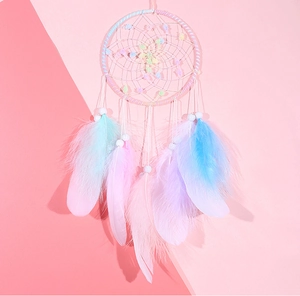 Close-up of handmade dreamcatcher featuring colorful gradient feathers and beaded ornaments