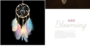 Close-up of bohemian dream catcher with multi-color feathers and warm LED fairy lights
