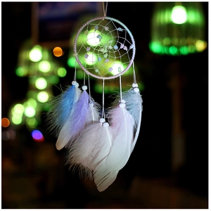 Close-up of a handmade dreamcatcher with macaron feathers and soft glowing bokeh light