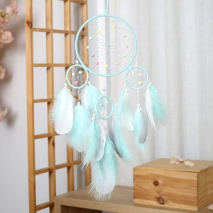 Mint green feather dream catcher with woven beads hanging in a cozy home interior