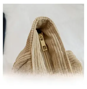 Detail shot of smooth gold zipper and corduroy fabric texture on beige tote bag