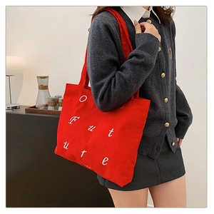 Close-up of red corduroy tote bag featuring white Future embroidery in a casual style
