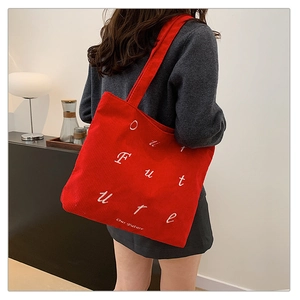 Detail of red corduroy tote bag showing Our Future text embroidery and ribbed texture