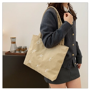 Detail of cream corduroy tote bag featuring white Future embroidery and wide shoulder strap