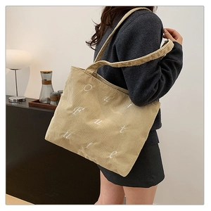 Detail of beige corduroy tote bag featuring white embroidered OUR FUTURE lettering