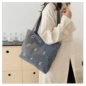 Detail of blue corduroy tote bag with white Our Future embroidery and striped texture