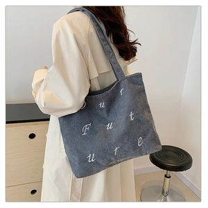 Close-up of blue corduroy tote bag featuring white Future embroidery and ribbed texture
