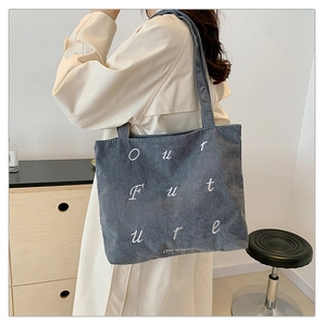 Detail of gray corduroy tote bag with Our Future embroidery and soft ribbed texture
