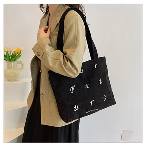 Detail of black corduroy tote bag featuring white Future embroidery and soft texture