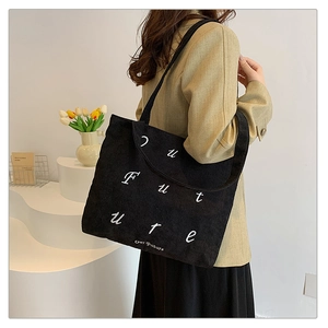 Detailed close-up of black corduroy tote bag featuring white Future text embroidery